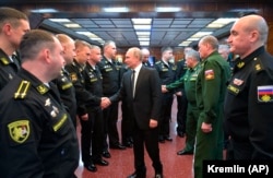 Vladimir Putin shakes hands with officers while visiting the a missile cruiser in the Black Sea.