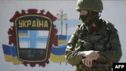 An armed man stands guard near a Ukrainian border guards base not far from the village of Perevalne, the site of a Ukrainian military base.