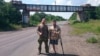 Denis Shchinkorenko (left) and Andrei Kamayev pose near a bridge painted with the word "Novorossia" in September 2015 in eastern Ukraine.