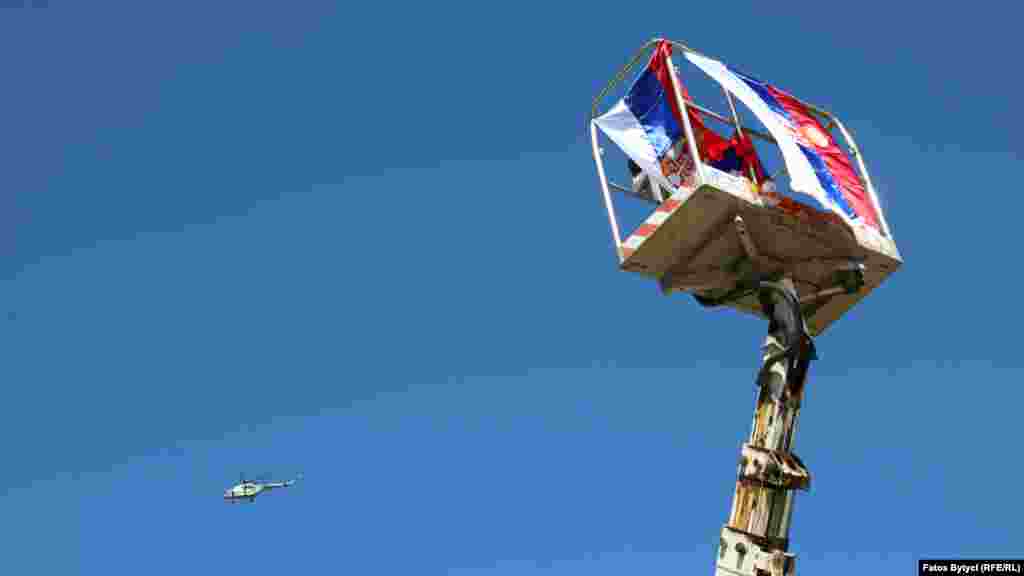 A NATO helicopter flies over a Serbian flag in Jarinje.