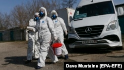 Workers wearing protective suits disinfect a public bus as a preventive measure against the coronavirus in the separatist-controlled city of Donetsk. 