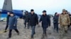 Members of an investigation committee and local officials walk past the wreckage of Azerbaijan Airlines' Flight J2-8243, which crashed in Aqtau in western Kazakhstan the previous day, killing dozens. 