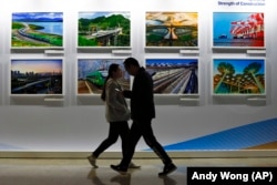 People walk by a display board showcasing China's construction projects at the media center of the Belt and Road Initiative in Beijing. (file photo)