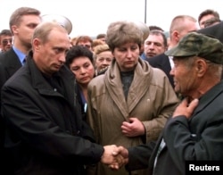 Vladimir Putin (left) shakes hands with an unidentified relative of a crew member of the submarine Kursk in the navy town of Vidyayevo on August 22, 2000.