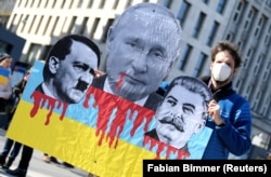 A protester holds a sign depicting Russian President Vladimir Putin, Adolf Hitler, and Josef Stalin during an anti-war demonstration in Hamburg, Germany, on March 20, 2022.