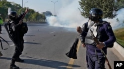 Pakistani police fire tear gas toward protesters marching toward Islamabad on November 26.