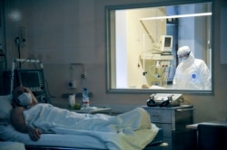 A doctor observes through a glass window the condition of a patient in a ward in the Moscow Sklifosovsky emergency hospital treating COVID-19 patients.