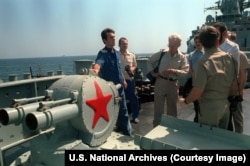 A Russian serviceman explains the operation of a chaff launcher, designed to baffle enemy radar to crew members from a U.S. aircraft carrier in October 1992.