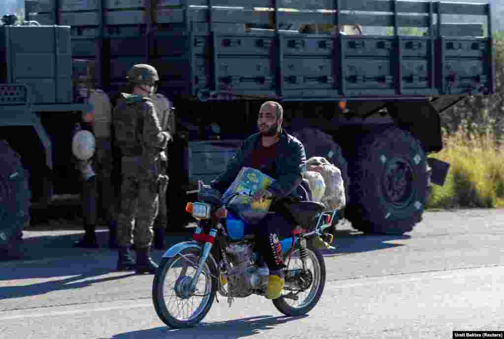 A local man rides past a Russian convoy near the Hmeimim air base.&nbsp; &quot;The locals are just watching,&quot; Bektas says of the situation around the base, which is now without external military protection along its perimeter. &quot;There are lots of shops with the Russian alphabet on them in the village close to the air base,&quot; Bektas says, but all are now closed. &quot;There aren&#39;t any Russian soldiers going out individually or in non-armored cars or anything like that.&quot; &nbsp;