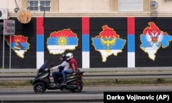 A motorbike passes a mural depicting (from left) the maps of Bosnia, North Macedonia, Kosovo, and Montenegro painted in the colors of the Serbian flag, in Belgrade on August 26.