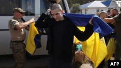 Ukrainian soldier Oleh Tipikin wraps himself in a Ukrainian flag after being released from Russian captivity at an undisclosed location near the Ukrainian-Belarusian border on September 13.