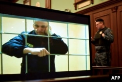 The late opposition leader Aleksei Navalny appears on a screen set up at a courtroom of the Moscow City Court via a video link from prison during a hearing on May 24, 2022.