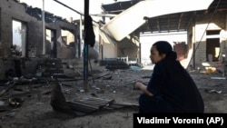 A woman sits outside her burnt-out house after the violence on February 7- 8.