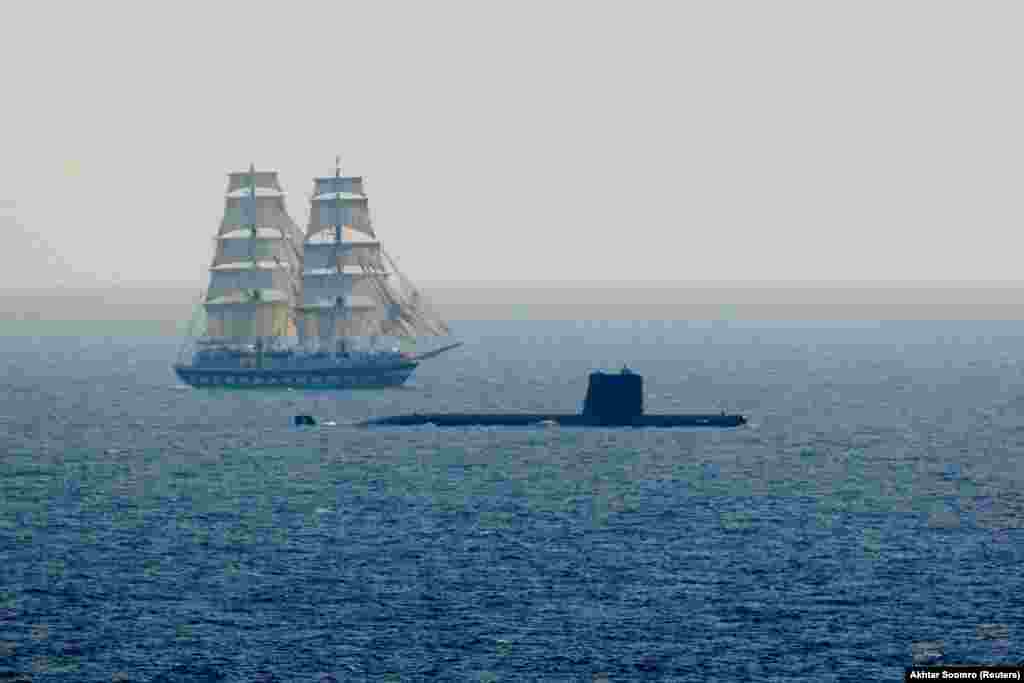 A naval submarine sails past a naval ship during the Pakistan Navy's 9th Multinational Maritime Exercise AMAN-25 in the Arabian Sea near Karachi, Pakistan.