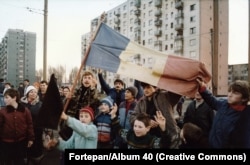 Romanians wave their country's flag with the communist coat of arms removed.