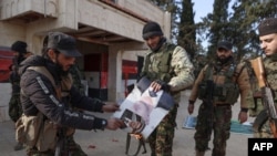 Members of Hayat Tahrir al-Sham set fire to a photo of ousted Syrian President Bashir al-Assad in Aleppo, northwestern Syria, on November 29.