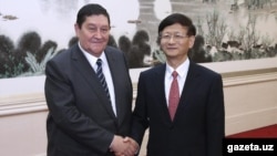 SNB chief Rustam Inoyatov (left) meets with an official in China in October 2014.