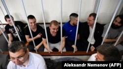 Ukrainian sailors sit inside a defendants' cage at a court hearing in Moscow on July 17.