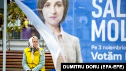 An elderly woman sits on a street bench behind a party campaign tent in downtown Chisinau ahead of a runoff in the presidential election. 