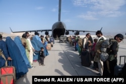 US Air Force personnel load passengers aboard a military cargo plane as part of the evacuation from Afghanistan in August 2021.