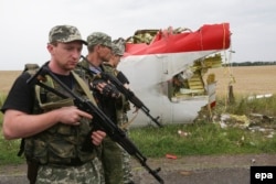 Armed pro-Russia militants walk past wreckage from MH17 near Donetsk on July 18, 2014.