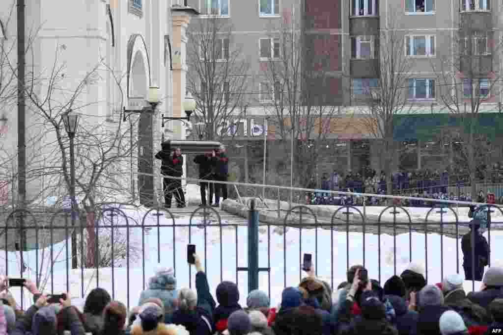 Pallbearers carry the coffin as mourners look on.&nbsp;