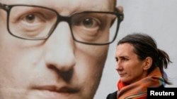 In Kyiv, a woman stands in front of a campaign poster with a portrait of Ukrainian Prime Minister Arseniy Yatsenyuk.