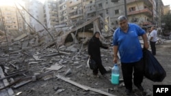 Residents carry some belongings as they walk amid the aftermath of an Israeli strike that targeted the Sfeir neighborhood in Beirut’s southern suburbs on October 6.