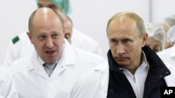 Businessman Yevgeny Prigozhin (left) shows Russian President Vladimir Putin around a St. Petersburg factory of his that produces school lunches.