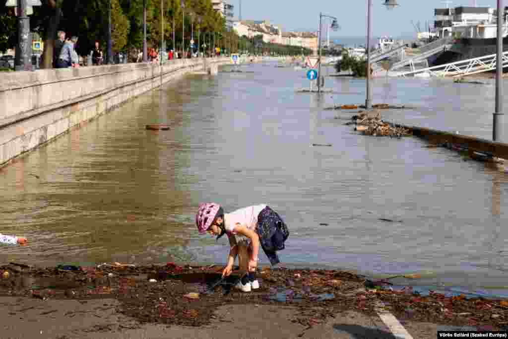 A child plays at the edge of a flooded riverside road in downtown Budapest.