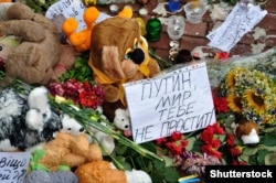 Flowers and toys near the Dutch Embassy in Kyiv in memory of those killed on MH17. The plane was shot down by a Russian missile, killing all 298 people aboard, including 80 children. The paper reads "Putin, the world won't forgive you" in Russian.