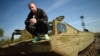 Dinko Valev, who owns a junkyard for trucks and buses, poses on one of his old military vehicles in the town of Yambol, some 240 kilometers from Sofia.