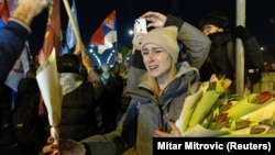 Students who marched to Novi Sad from Belgrade are handed flowers as they arrive at the site of a fatal railway station roof collapse.