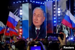 Russian President Vladimir Putin appears on a screen of the stage as he attends a rally marking the 10th anniversary of Russia's illegal annexation of Crimea from Ukraine, in Red Square in central Moscow on March 18.