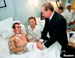 Then-Prime Minister Vladimir Putin speaks to a Russian soldier wounded in Chechnya at a military hospital outside Moscow on December 28, 1999.