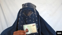 An Afghan woman shows her voter registration card.