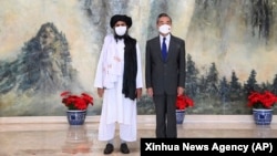 Taliban co-founder Mullah Abdul Ghani Baradar (left) and Chinese Foreign Minister Wang Yi pose for a photo during their meeting in Tianjin in July. 