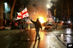 A man waves a Georgian flag in front of a burning barricade during protests against an earlier draft version of the bill, in Tbilisi in March 2023.