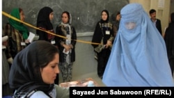 At a Kabul polling station, an election worker cleans and applies ink on a voter's finger 