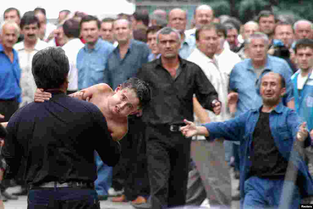 A man carries an injured boy to safety.