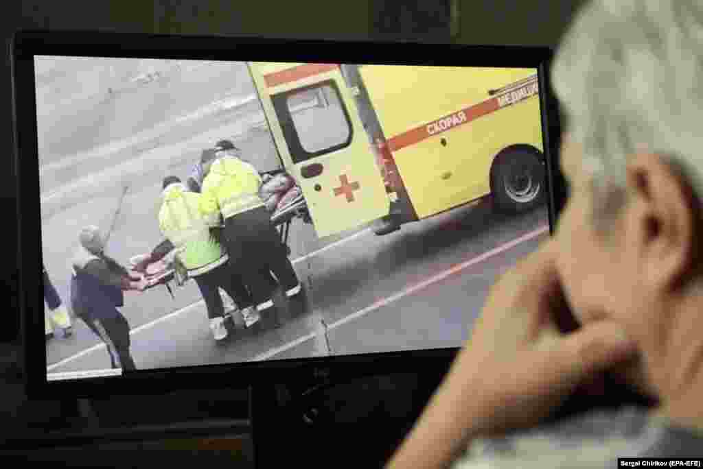 A person watches a video on social media showing Navalny being carried on a stretcher by an ambulance team in Omsk after falling gravely ill from suspected poisoning while aboard a flight from Tomsk to Moscow on August 20.