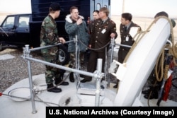 A U.S. Army interpreter translates for Russian Strategic Rocket Forces colonels at the entrance to an access shaft into a Minuteman III nuclear missile silo.