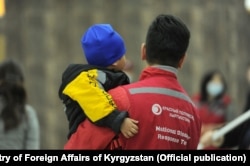 A Red Crescent worker holds a child who has returned from Iraq to Kyrgyzstan. (file photo)