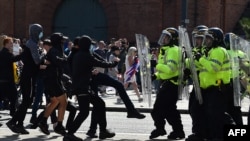 Police officers face protesters in Liverpool, England, on August 3, 2024, at a demonstration held in reaction to the fatal stabbings in Southport on July 29. Europe Invasion falsely suggested the attacker was a “Muslim immigrant,” and London’s police chief said the riots were “driven by misinformation.”