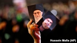 A Hezbollah supporter holds up portraits of Hezbollah leader Hassan Nasrallah and Iranian Supreme Leader Ayatollah Ali Khamenei in Beirut.