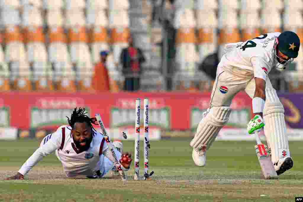 West Indies&#39; Jomel Warrican (left) runs out Pakistani captain Shan Masood during a Test cricket match in Multan, Pakistan. .