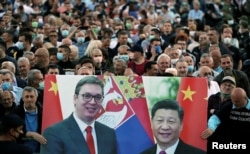 Government supporters hold a banner of Serbian President Aleksandar Vucic (left) and Chinese President Xi Jinping at a demonstration outside parliament in Belgrade in May 2020.