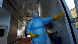 A member of the medical staff sprays disinfectant inside an ambulance at the Vishnevskiy hospital in Donetsk.