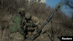 Ukrainian servicemen fire a mortar on the front line in Bakhmut. 