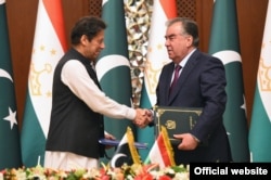 Pakistani Prime Minister Imran Khan (left) and Tajik President Emomali Rahmon shake hands at their meeting in Dushanbe on September 17.